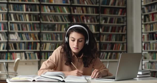 Spansktalande kvinna student i headset förbereda kursarbete med hjälp av böcker bärbar dator — Stockvideo