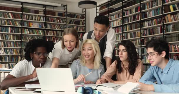 Grupo de diversos alunos que estudam na biblioteca usando brainstorming laptop — Vídeo de Stock