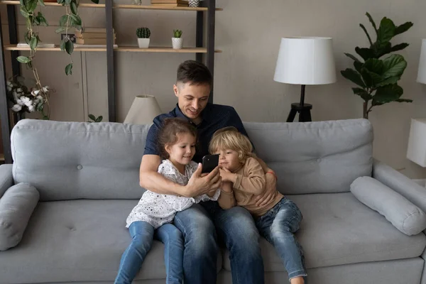 Affectueux père aimant et les petits enfants en utilisant un téléphone portable à la maison. — Photo