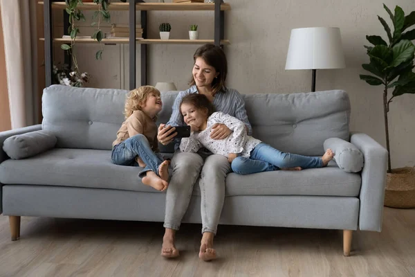 Petits enfants joyeux utilisant un téléphone portable avec maman. — Photo