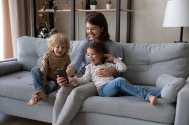 Küçük çocukların telefonunu kullanan mutlu genç bir anne..
