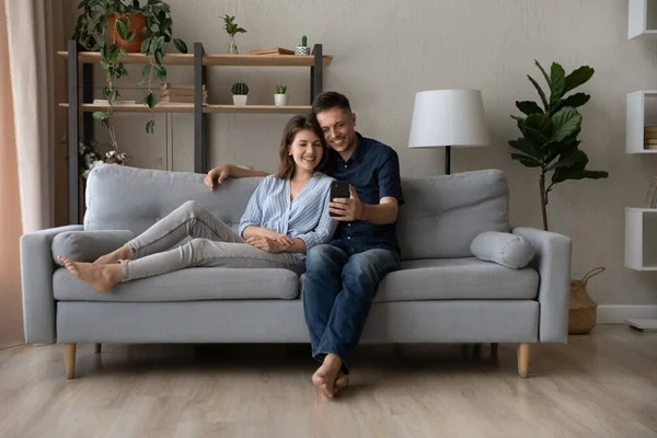 Relajado feliz joven familia pareja usando smartphone. — Foto de Stock