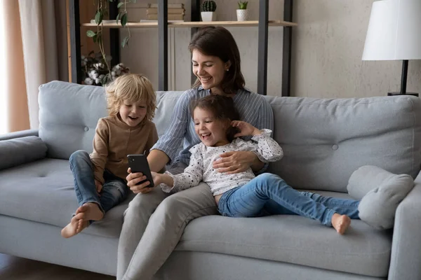 Bonne jeune mère en utilisant le téléphone avec de jeunes enfants. — Photo