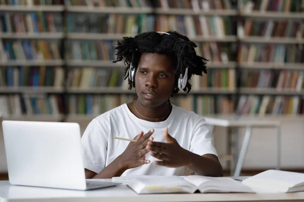 Concentrado jovem afro-americano estudante do sexo masculino e-learning na biblioteca. — Fotografia de Stock