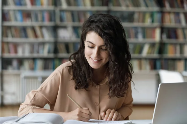 Gelukkige jonge Spaanse vrouw studeert in de bibliotheek. — Stockfoto