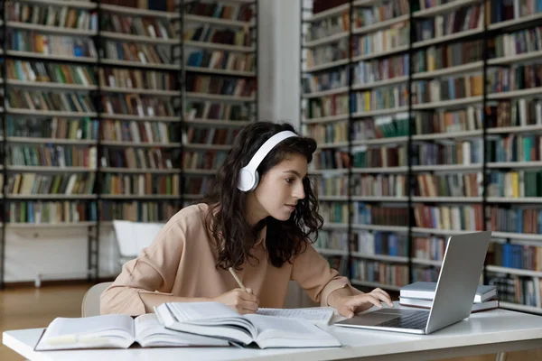 Glad söt tusenårig spansktalande kvinna e-lärande i biblioteket. — Stockfoto