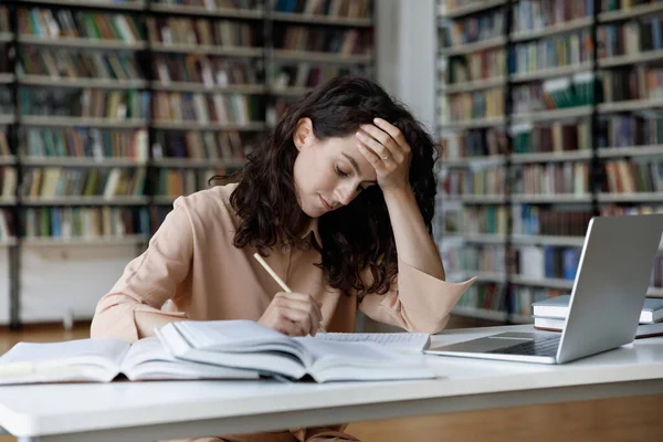 Olycklig stressad ung spansktalande kvinna trött studera i biblioteket. — Stockfoto