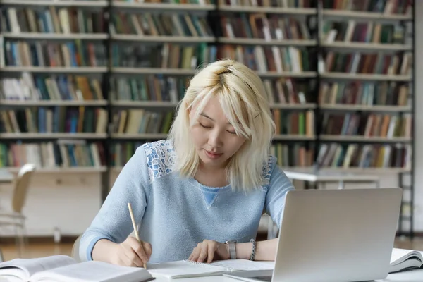 Geconcentreerde slimme Aziatische vrouw studeren in bibliotheek. — Stockfoto