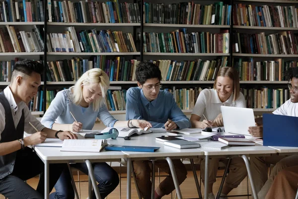 Grupo enfocado de estudiantes felices y diversos que estudian en la biblioteca. —  Fotos de Stock