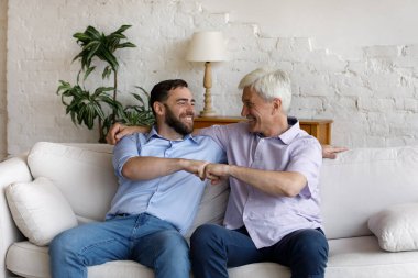 Yaşlı ve genç erkekler kanepede oturur ve yumruk tokuştururlar.