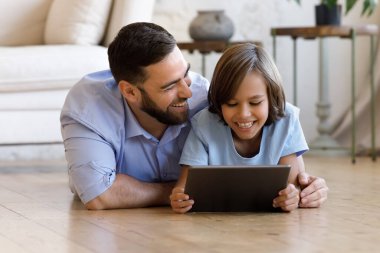 Baba ve oğul dijital tablet kullanarak yerde yatıyorlar.