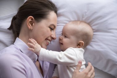 Mutlu genç anne ve tatlı neşeli bebek yatak odasında dinleniyor.