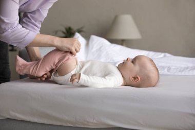 Anneciğin elleri küçük tatlı bir bebeği sürüngen gibi giydiriyor.