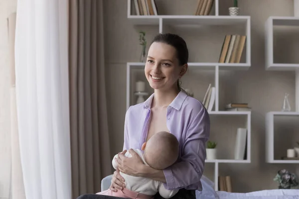 Happy young mom breastfeeding baby at home — Stock Photo, Image