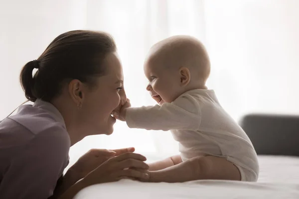 Vreugdevolle jonge moeder spelen met baby thuis, genieten van het moederschap — Stockfoto