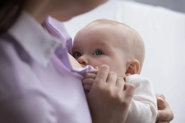 Joven mamá amamantando dulce bebé, sentado, sosteniendo al bebé en brazos — Foto de Stock