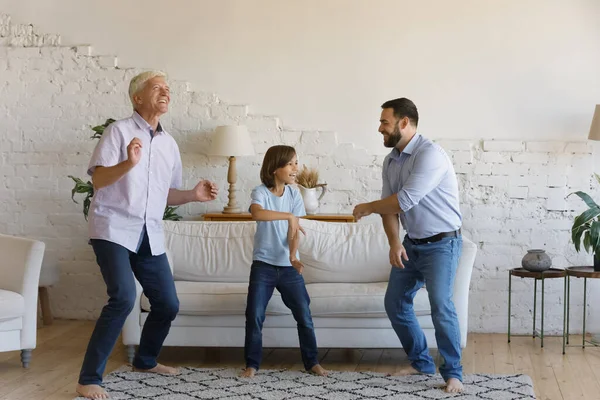 Pequeño niño su abuelo mayor y padre bailando juntos en interiores —  Fotos de Stock