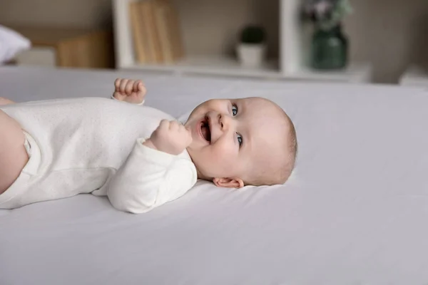 Happy cheerful few month baby resting on white linen — Stock Photo, Image