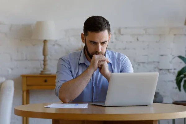 Hombre serio leer e-mail en el ordenador portátil parece preocupado o perplejo —  Fotos de Stock