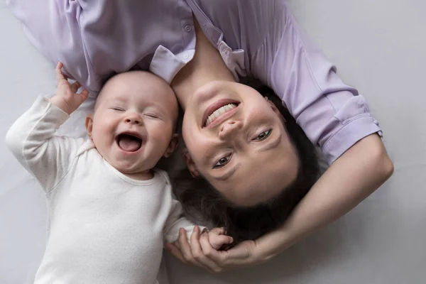 Happy mother and few month baby resting on big bed — Stock Photo, Image