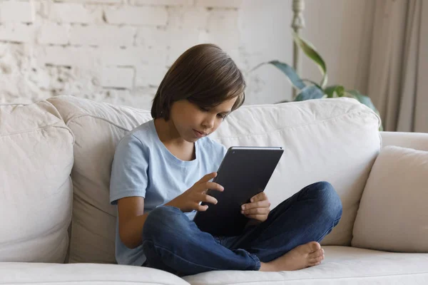 Ferdig tenåringsgutt sitter på sofaen med digitale nettbrett – stockfoto