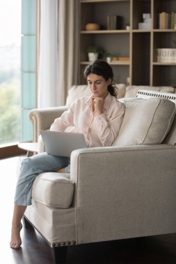 Evde bilgisayar kullanan konsantre genç İspanyol kadın..