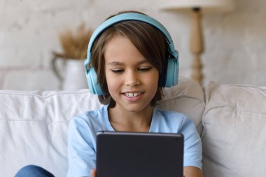 Çekici küçük çocuk kulaklık takıyor. Dijital tablet kullanarak iyi eğlenceler.