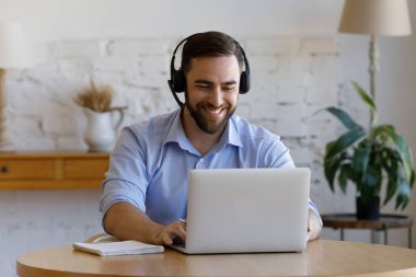 Kulaklık takan adam e-öğreniyor, sanal iş toplantısına katılıyor.