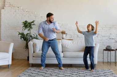 Genç baba ve küçük oğul evde dans ediyor.