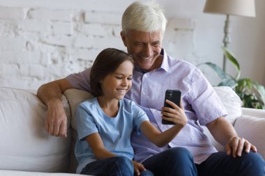Büyükbaba küçük torunu modern akıllı telefonu kullanarak eğleniyor.