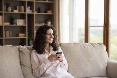 Akıllı telefon kullanan rüya gibi, mutlu, genç bir İspanyol kadın..
