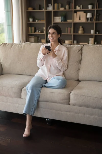 Relaxado milenar mulher hispânica usando celular em casa. — Fotografia de Stock