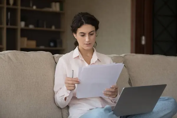 Concentré jeune femme hispanique intelligente travaillant avec des documents papier. — Photo