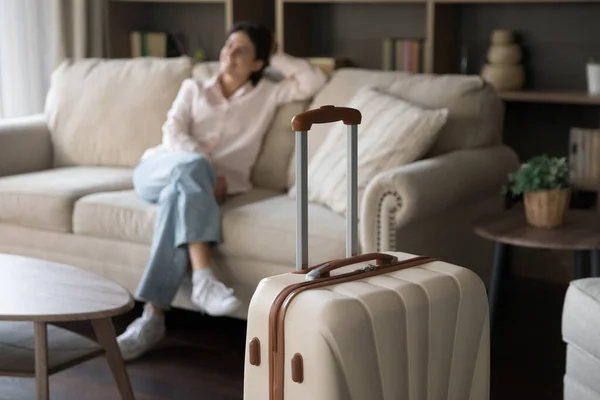 Фокус на бежевій валізі з розмитою розслабленою жінкою на фоні . — стокове фото