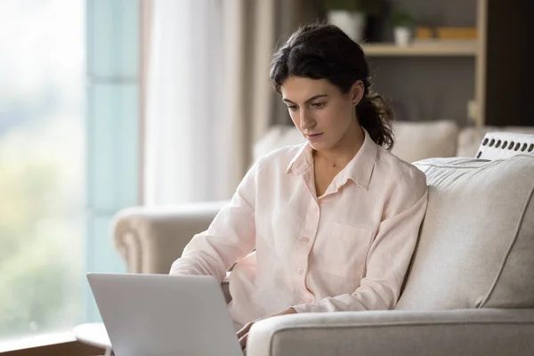 Mujer hispana joven y concentrada que trabaja en la computadora en casa. — Foto de Stock