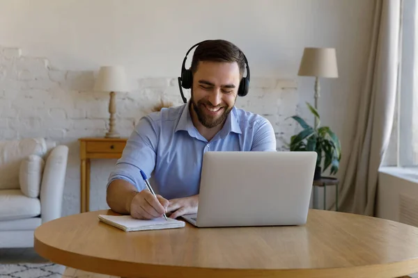 Man zit achter bureau met laptop maakt aantekeningen in het kopieerboek — Stockfoto