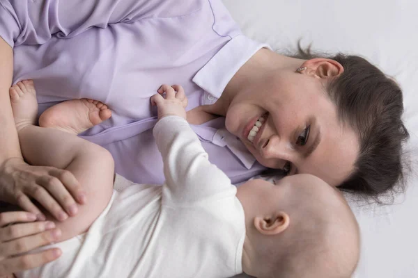 Feliz cuidado dedicado nueva mamá disfrutando de la relajación con el bebé —  Fotos de Stock