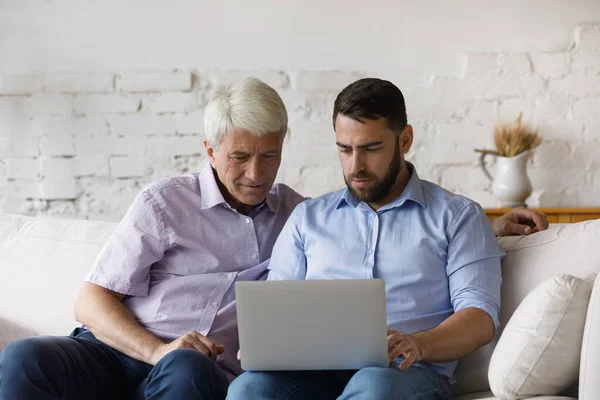 Komoly Y-generációs férfi segít az idősebb apa laptop használat — Stock Fotó