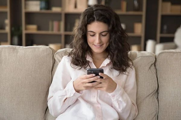 Relaxado atraente mulher hispânica usando celular em casa. — Fotografia de Stock