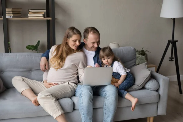 Heureux attendant parents et petite fille enfant se détendre sur le canapé — Photo