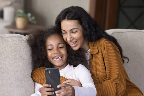 Riendo mamá afroamericana y su hija usando el teléfono celular. — Foto de Stock