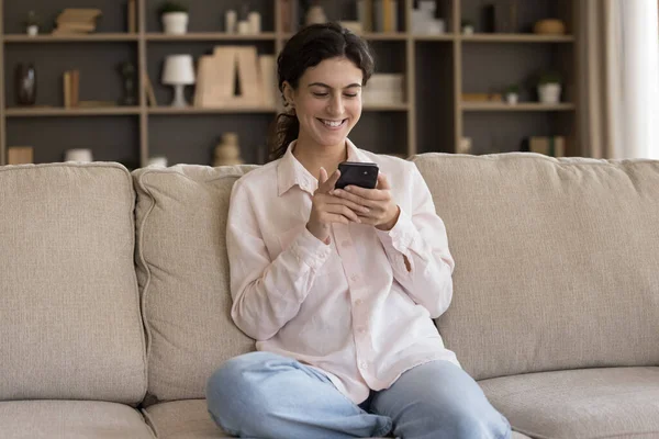 Lachende mooie jonge Spaanse vrouw met behulp van smartphone. — Stockfoto