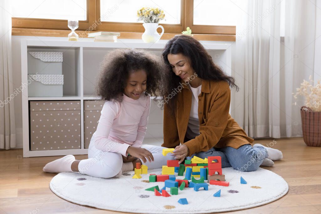 Happy preteen African American girl playing toys with mother.