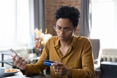 Endişeli Afrikalı kredi kartı kullanıcısı kadın cep telefonunda online ödeme uygulamasında sorun yaşıyor. Endişeli banka müşterisi şaşkın, sıkıntılı sanal finans hizmeti hatası, hata