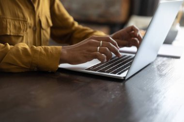 Dizüstü bilgisayarda çalışan Afrikalı kadın çalışan, klavyede yazan. Kadın elleri yakın. Gündelik, profesyonel bir iş kadını masada çalışıyor, online uygulama kullanıyor, sohbet ediyor, makale yazıyor. Kırpılmış atış