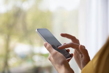 Kapalı görüşlü kadın elleri modern akıllı telefonu tutuyor, mesaj yazıyor, sosyal medyada mesajları paylaşıyor, tebligatı okuyor. Kablosuz teknik kullanım, mesafe iletişimi, uygulama kavramı
