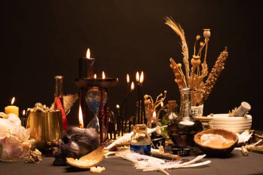 Büyülü eşyalarla dolu bir cadı masası. Önde seçici odaklanma. Kara büyü kafatası mumu, ritüel insan dişleri, kuş tüyü, iksir şişeleri, kum saati ya da kum saati olan bir hayat. Cadılar Bayramı.