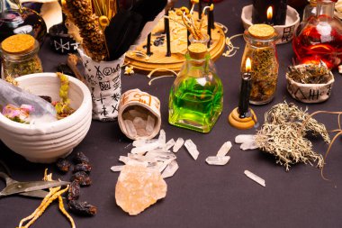 Büyülü eşyalarla dolu bir cadı masası. Önde seçici odaklanma. Kara büyü mumu, ritüel kristal taşlar, kuru mantar otları, iksir şişeleri ve sihirli mantarlarla dolu bir hayat. Cadılar Bayramı.