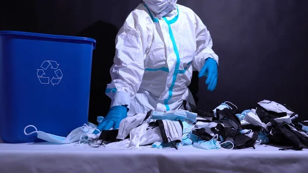 Coronavirus trash on the table. Disposable medical masks used personal protective equipment pile. Surgical bio hazard waste disposal due COVID-19 pandemic.