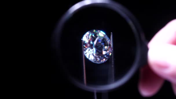 ゴールドスミスの手は虫眼鏡で豪華な鮮やかなダイヤモンドの品質を検査します 選択的焦点マクロ 品質検査 婚約指輪または結婚指輪用ラウンドダイヤモンド — ストック動画